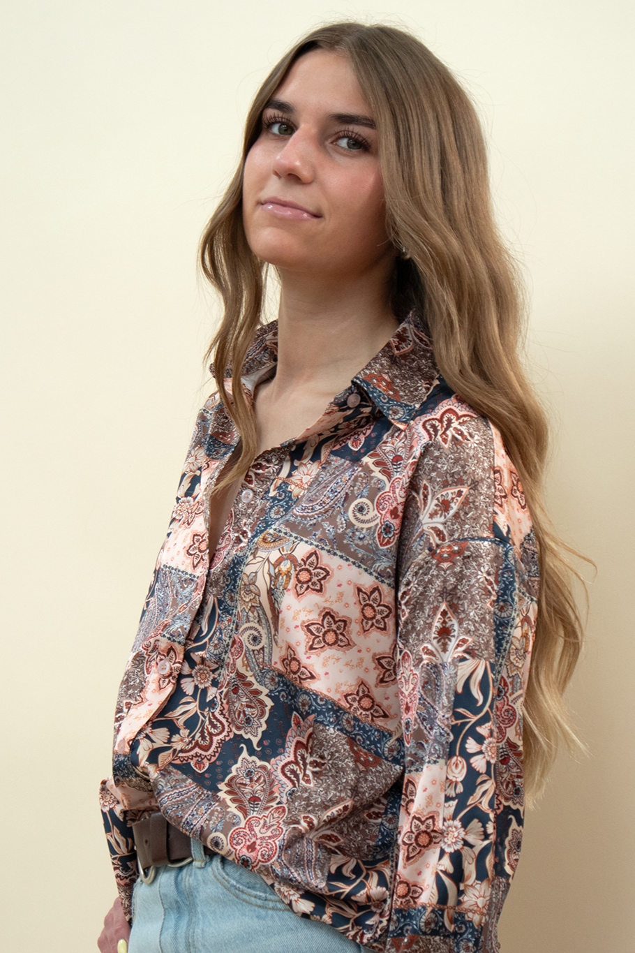 Close-up of a woman wearing a satin patchwork button-up blouse with floral and paisley print in warm earth tones—boho-style long sleeve shirt ideal for fall outfits or statement layering pieces.