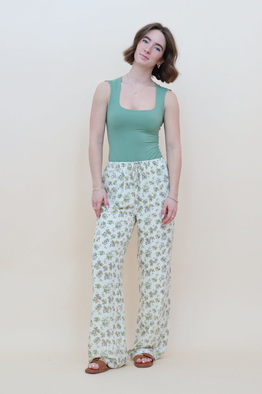 Cream pants with green and blue floral pattern and a drawstring waist with pockets