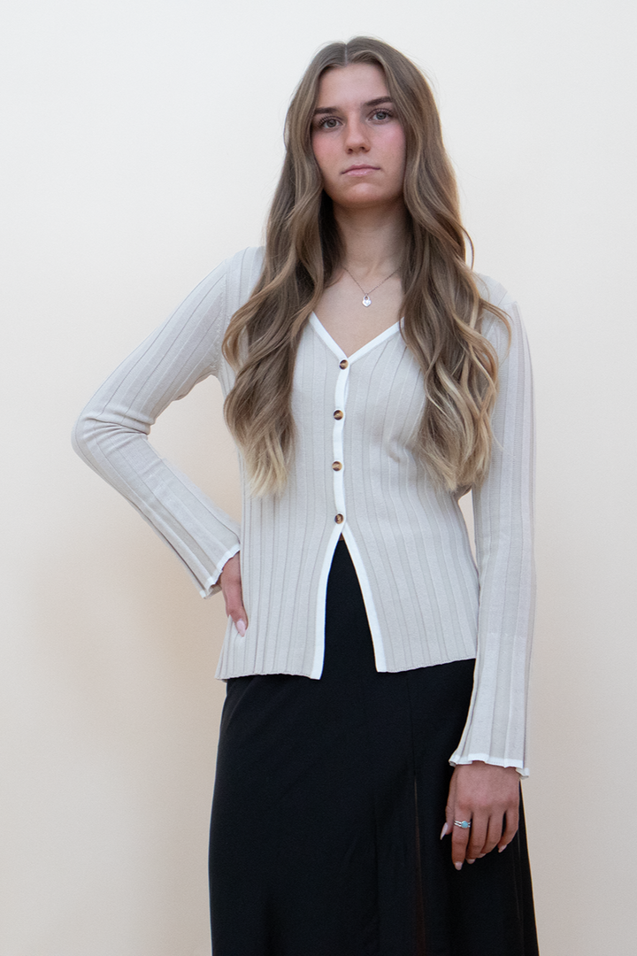 beige bell sleeve knit button up, styled with a black skirt