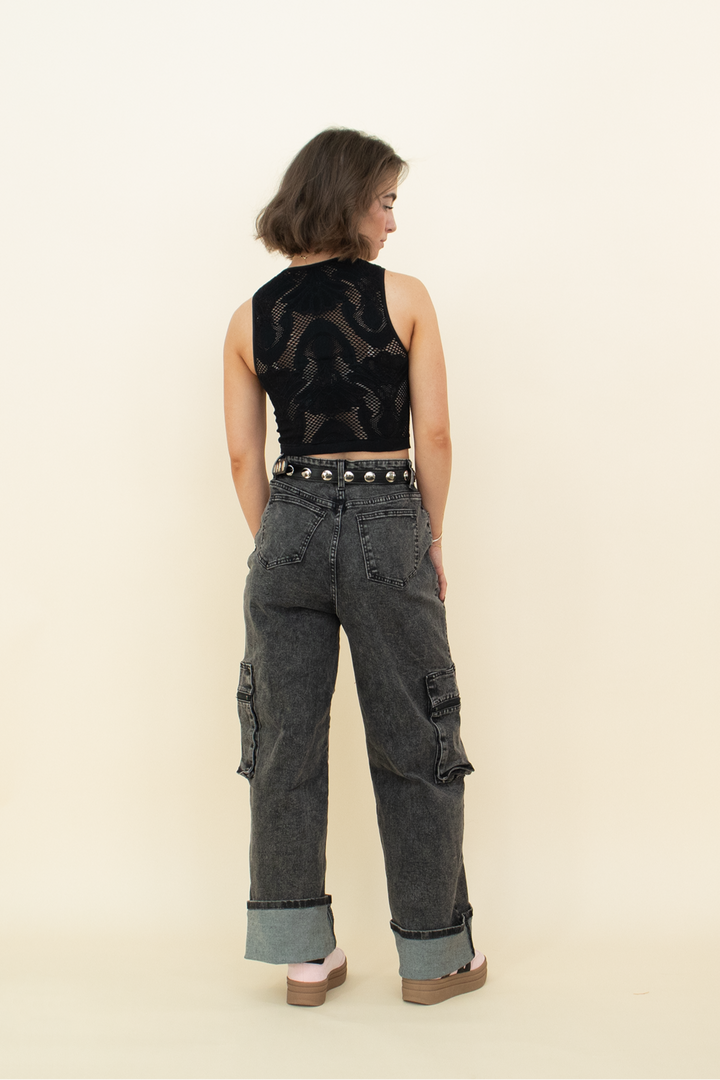 black acid wash cargo pants as seen from the back, styled with a black studded belt, pink shoes and a black fishnet tank