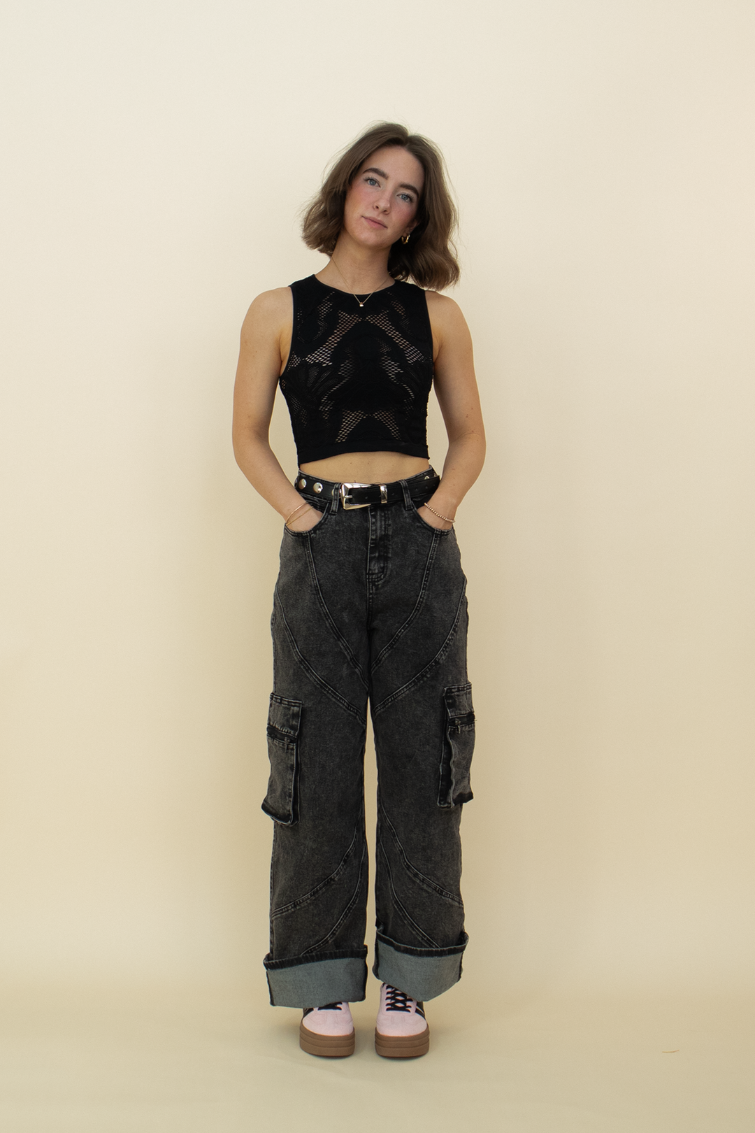 black acid wash cargo jean with extra seam detailing, styled with pink sneakers and a black fishnet tank
