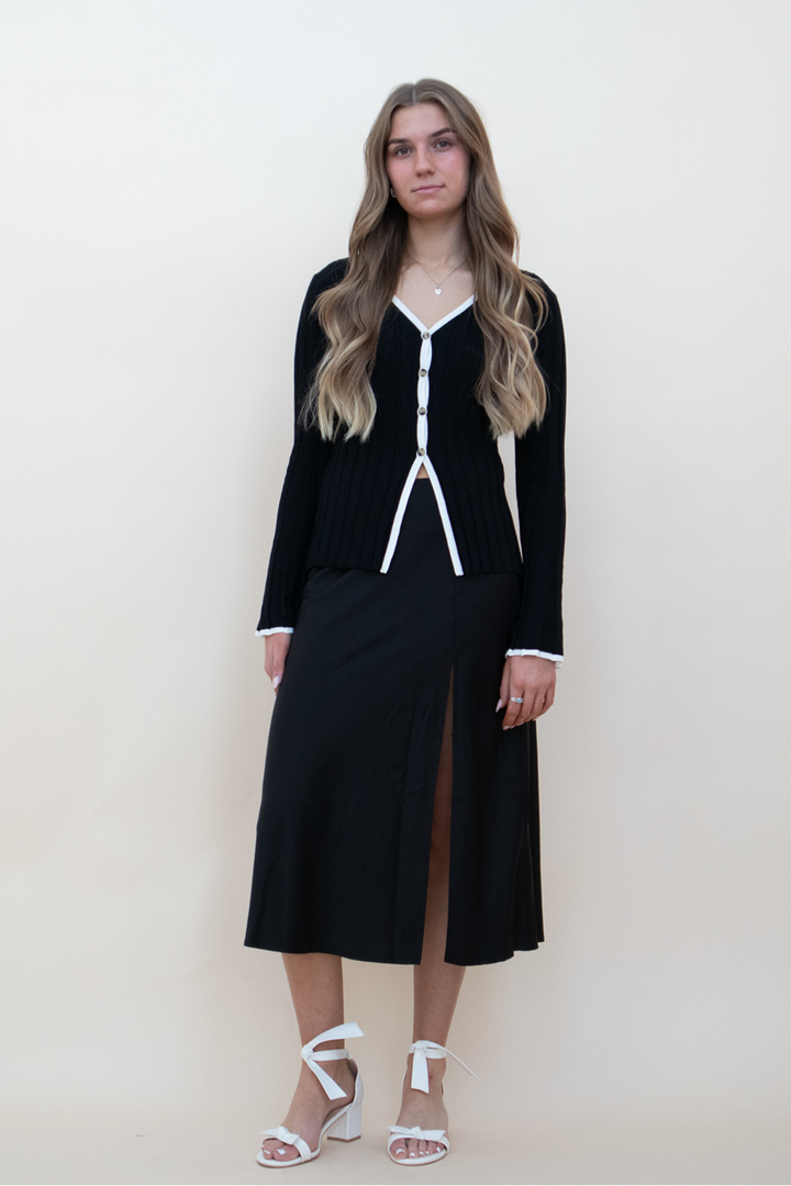black knit button up, styled with a black silk skirt and a white heel