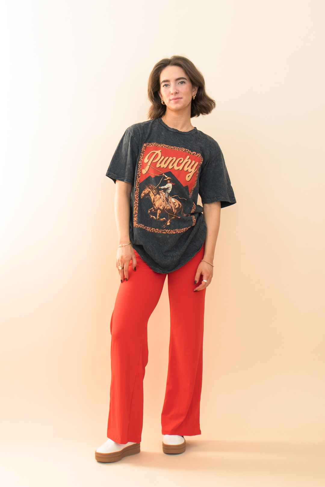 black acid wash graphic tee with a cowboy on it, styled with red lounge pants and a white sneaker