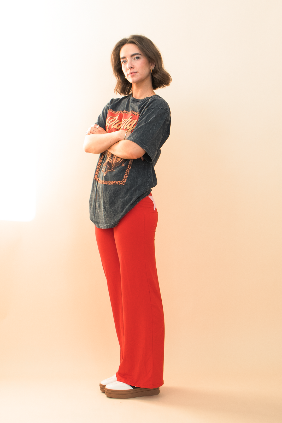 black acid wash "punchy" graphic tee, styled with red star pants and a white sneaker.