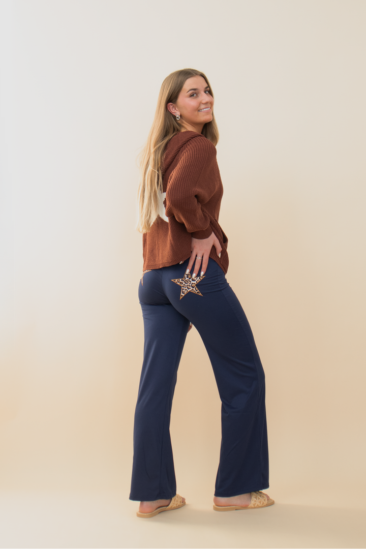 Rear view of a woman wearing a green waffle knit hoodie with a white star graphic on the back, styled with faded denim cargo shorts. Casual and cozy streetwear outfit for women, perfect for fall layering, music festivals, or off-duty days. Trendy aesthetic ideal for Gen Z and millennial fashion lovers.