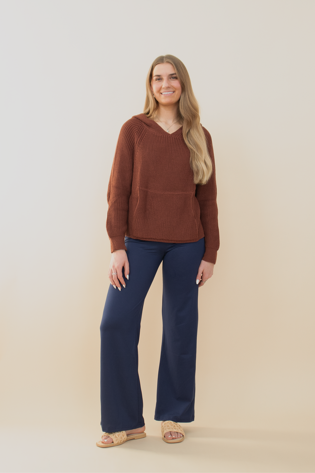 Smiling woman posing in a chocolate brown waffle knit hoodie with a white star on the back, paired with distressed denim cargo shorts. Trendy casual outfit for young women, ideal for transitional weather, weekend outings, or laid-back street style. Gen Z-approved fashion with cozy and playful vibes.