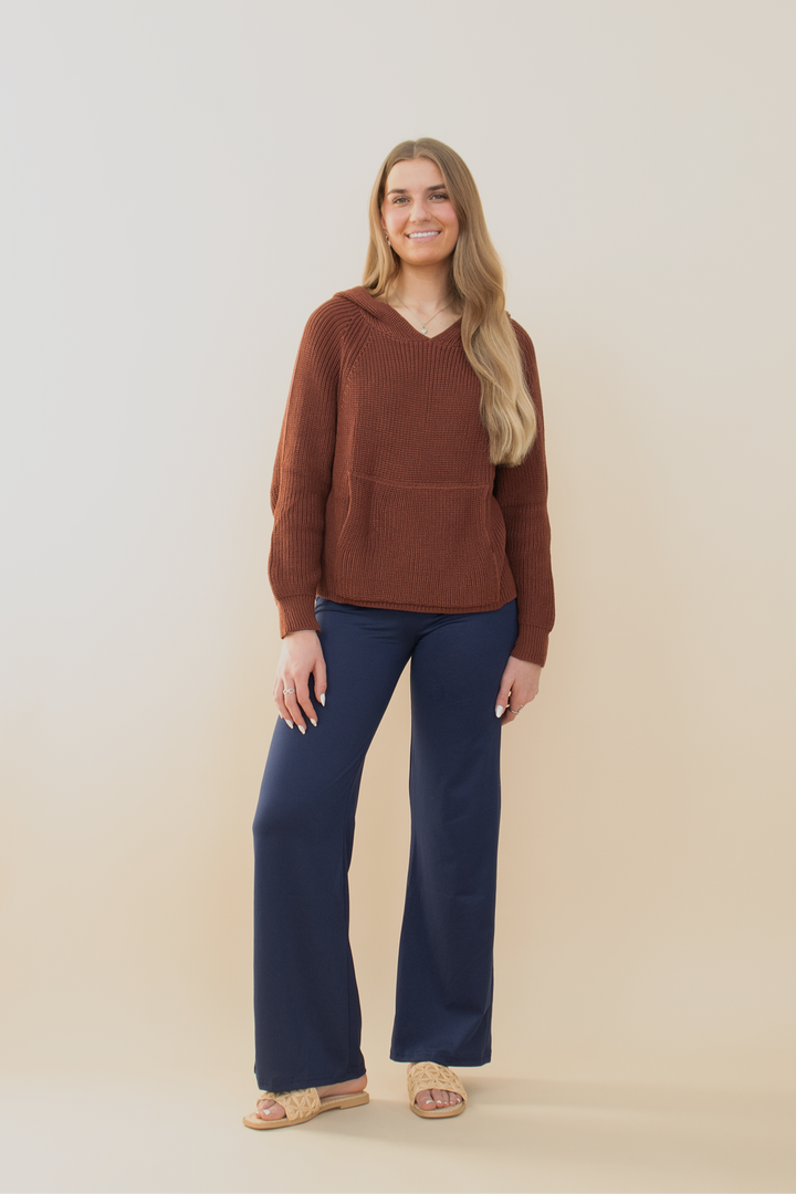 Smiling woman posing in a chocolate brown waffle knit hoodie with a white star on the back, paired with distressed denim cargo shorts. Trendy casual outfit for young women, ideal for transitional weather, weekend outings, or laid-back street style. Gen Z-approved fashion with cozy and playful vibes.