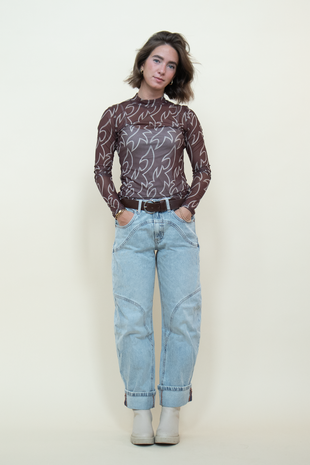 Front view of a sheer brown mesh long-sleeve top with a mock neckline and cream Western-inspired graphic print.