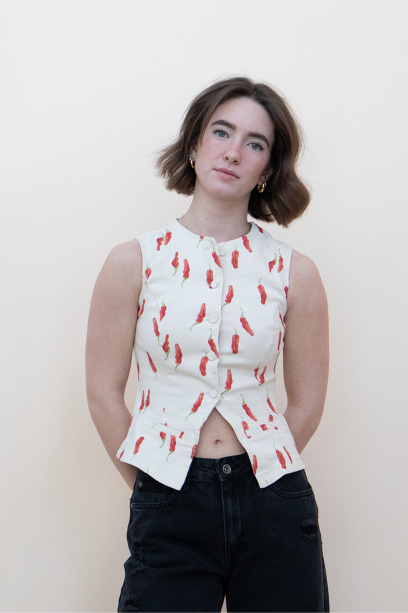 Front view of a sleeveless white button-up top with red chili pepper print, styled with high-rise black distressed jeans — playful and bold women’s summer fashion piece.