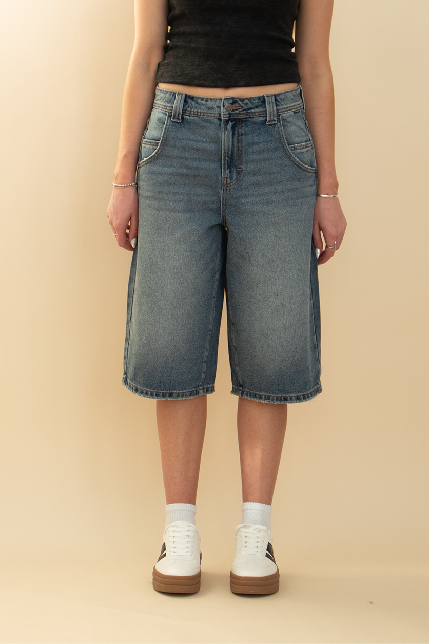 long denim jort in gray blue washed color, styled with a white sneaker and black top
