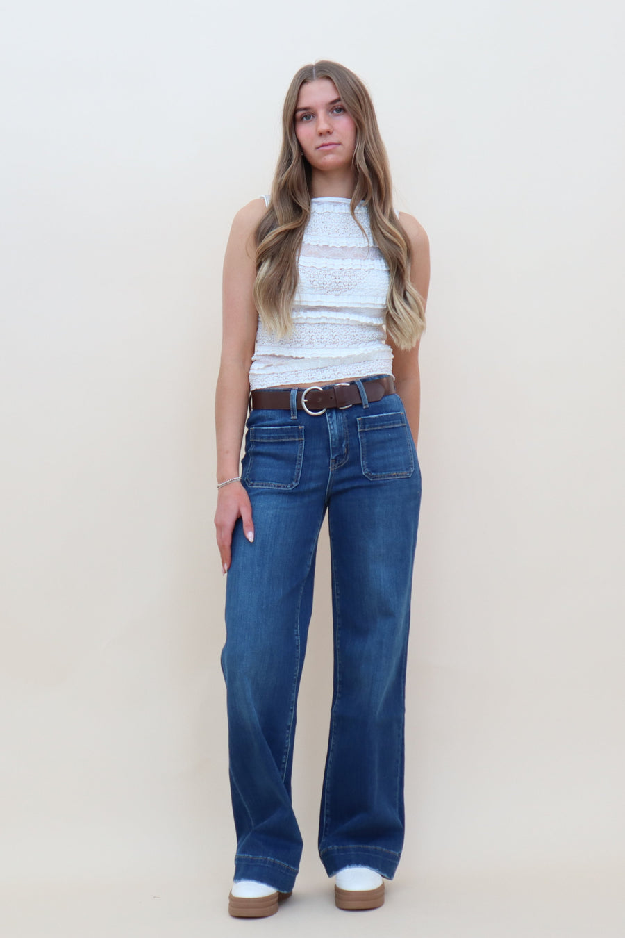 Sheer white lace patchwork top with ruffles incorporated, paired with a blue jean and white sneakers
