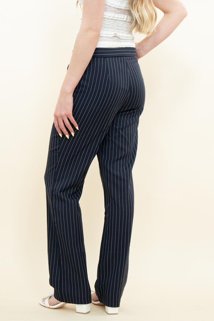 Back view of Groove Closet navy pinstripe wide-leg trousers, tailored fit with subtle vertical stripes, styled with white heels.