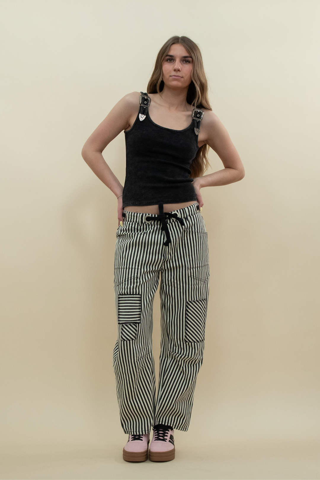 Woman wearing black and white striped barrel jeans with patchwork detail, styled with a black tank top and pink platform sneakers – Groove Closet product photo.