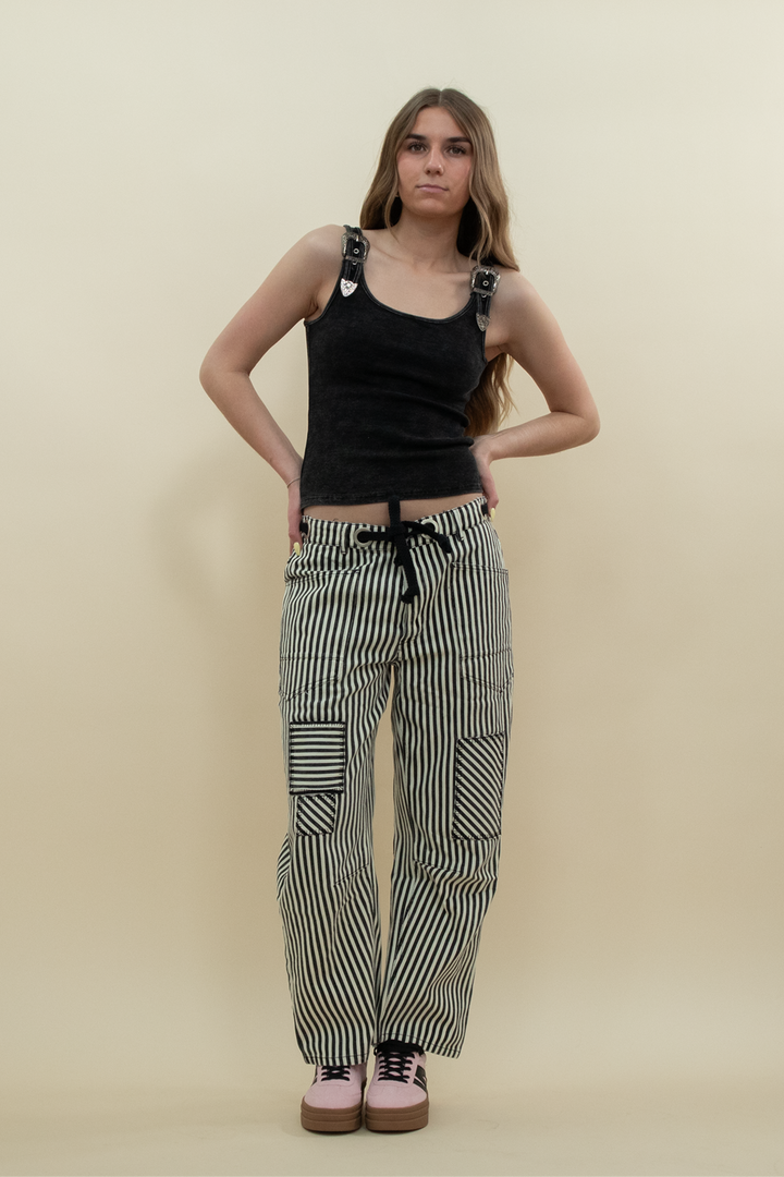 Woman wearing black and white striped barrel jeans with patchwork detail, styled with a black tank top and pink platform sneakers – Groove Closet product photo.