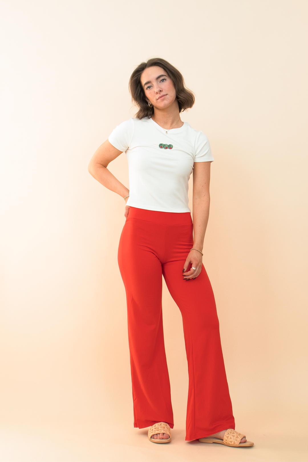 Bold summer outfit featuring vibrant red flared pants and a white baby tee with cherry embroidery, perfect for casual chic streetwear style.