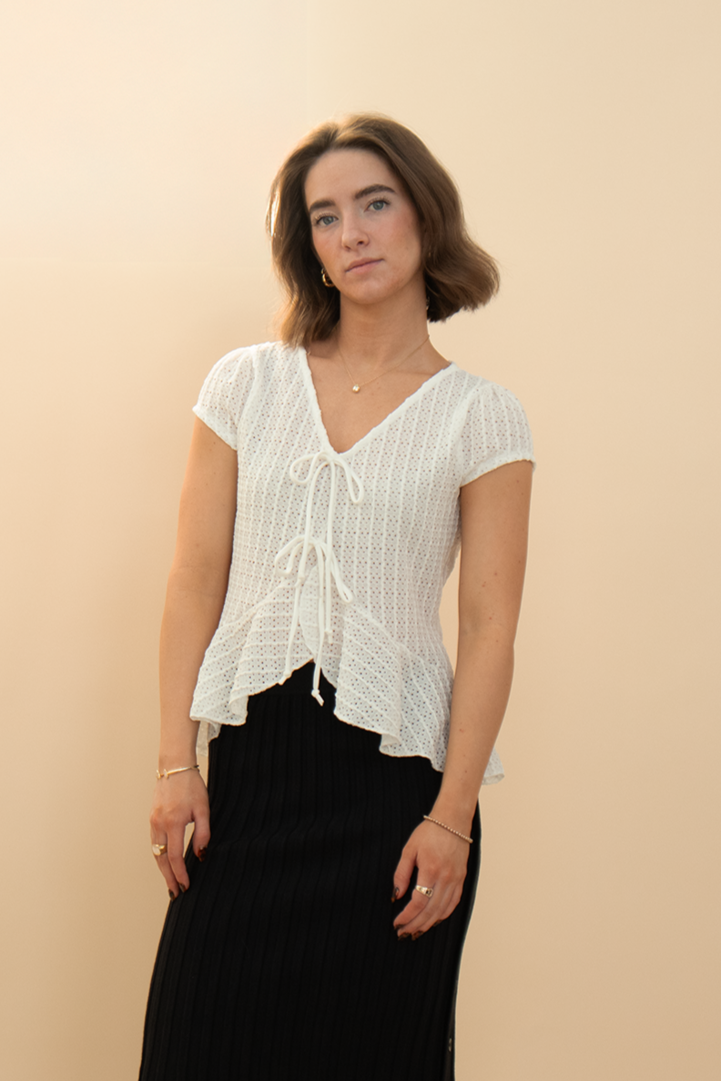White cap sleeve eyelet peplum top with bow accents styled with a black pencil skirt, chic and trendy women's outfit.