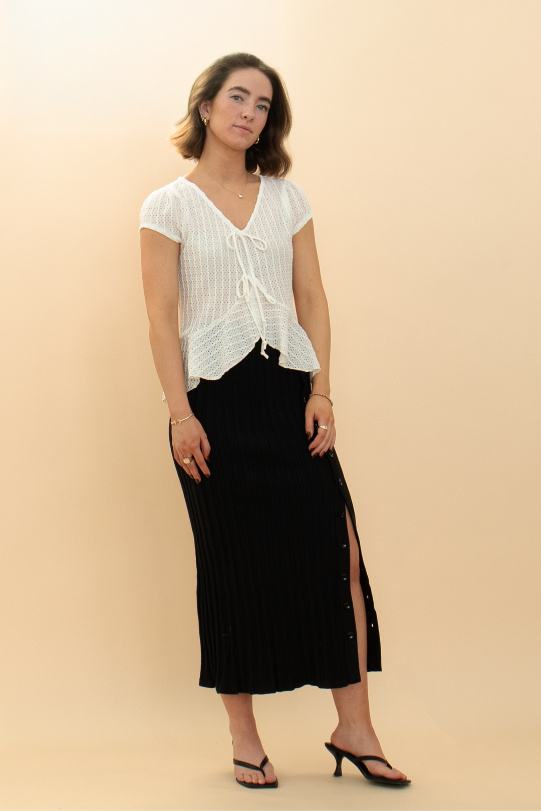 Chic white cap sleeve eyelet peplum top paired with a black pencil skirt featuring a slightly unbuttoned detail for a relaxed look.