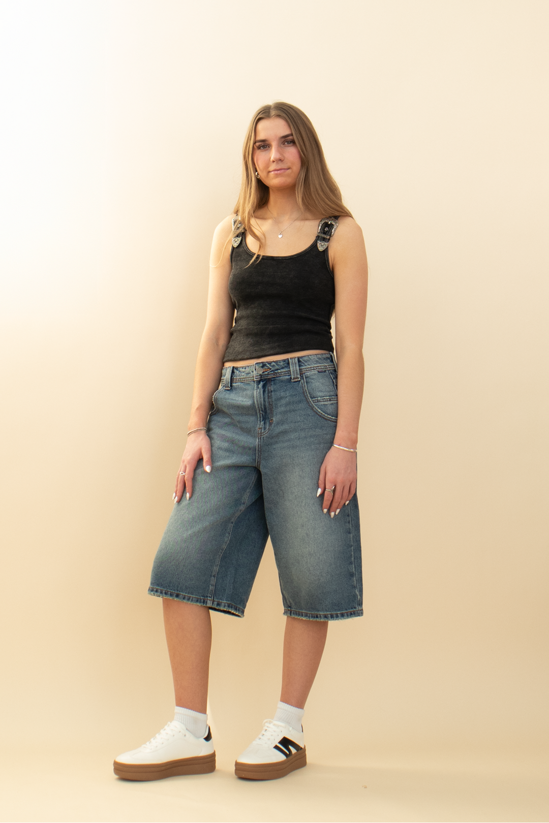 wide leg denim jort styled with white sneakers and a black tank top
