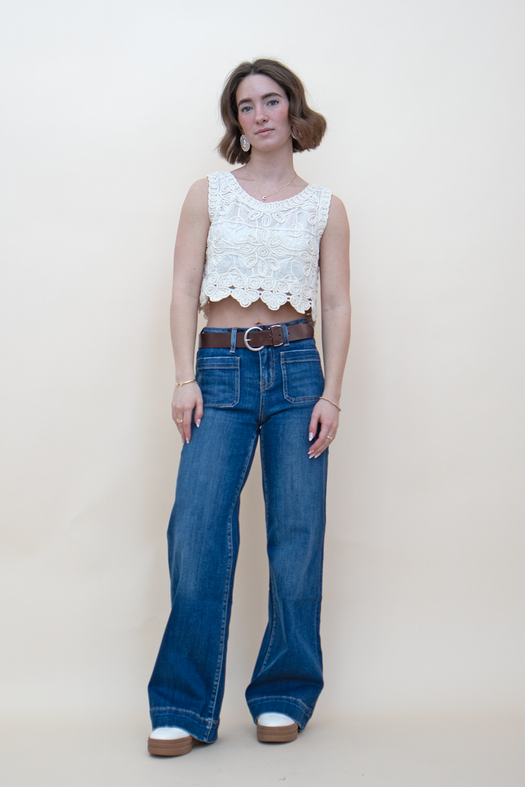 blue denim wide leg jean with defined outline pockets, styled with an ivory floral crop tank and a brown belt