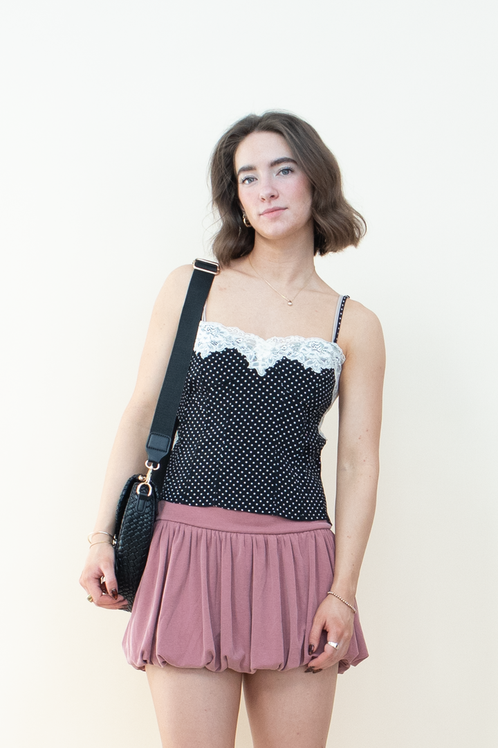 Close up of black polka dot spaghetti strap cami top with scalloped white lace trim neckline detail