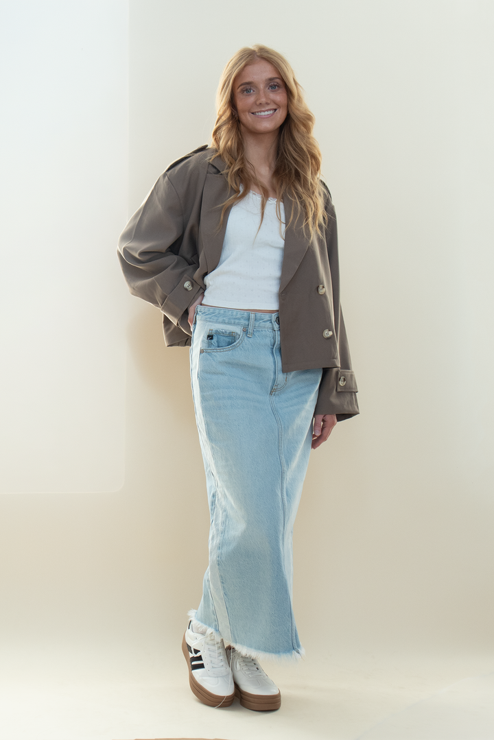 Cropped taupe trench jacket with statement sleeves paired with a frayed hem denim maxi skirt and white sneakers