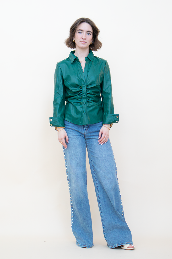 Model wearing an emerald green leather-look button-up top with ruched front detailing, collared neckline, and long sleeves.
