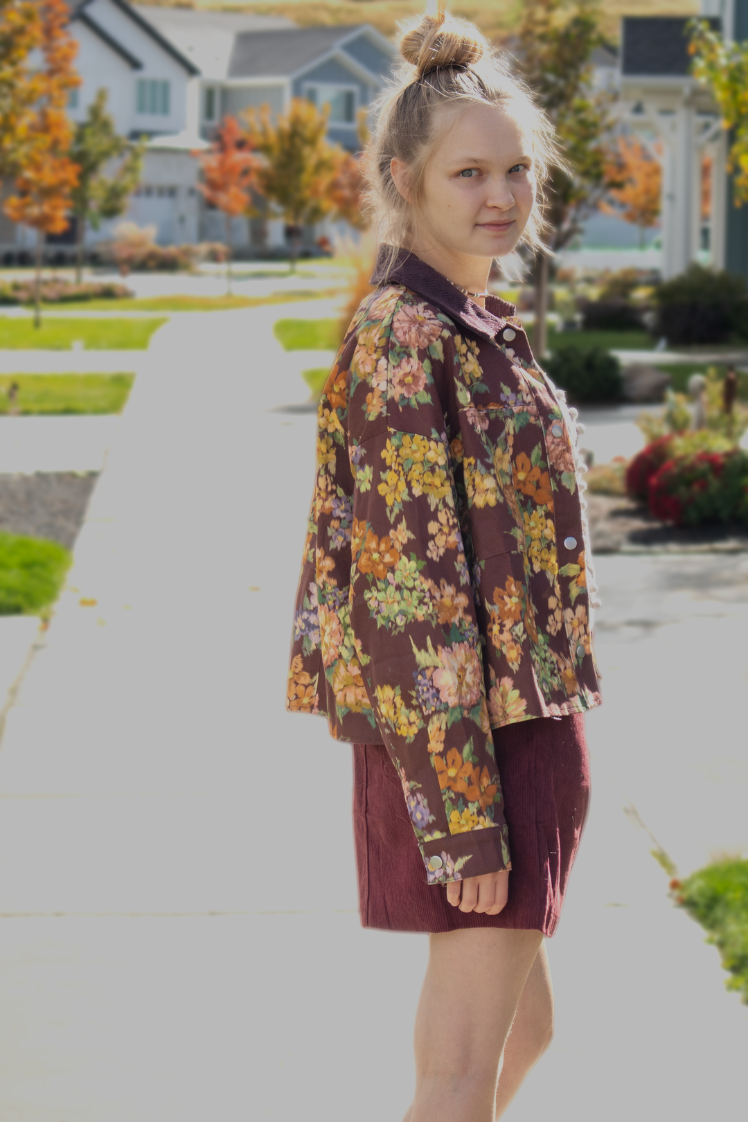 Model wearing a maroon floral jacket with a relaxed fit, corduroy collar, snap-button front, and oversized autumn floral print.